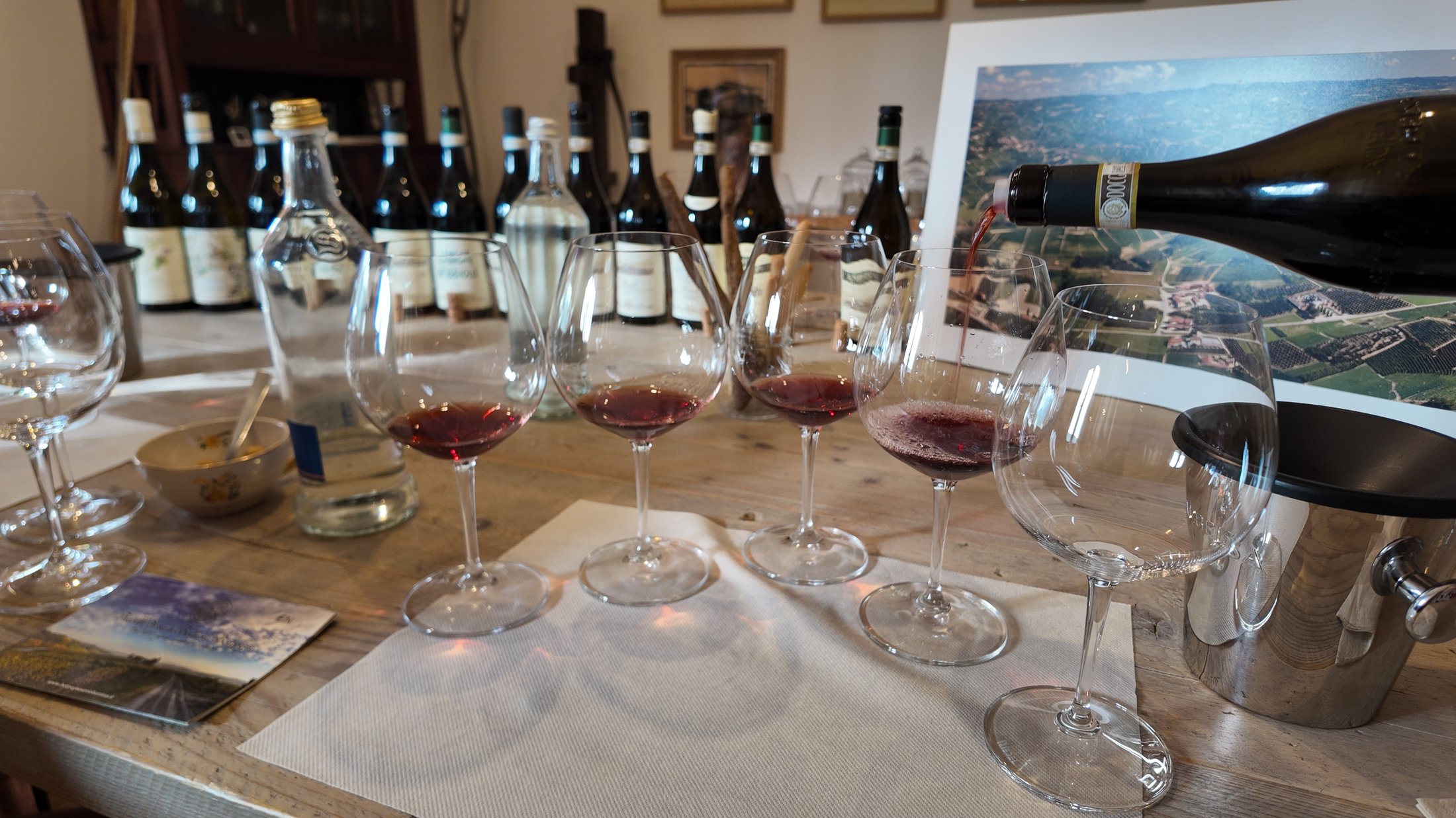 Degustace u stolu — nalévání červeného vína do sklenek